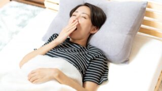 ベッドであくびする女性の画像