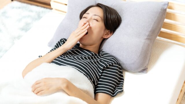 ベッドであくびする女性の画像