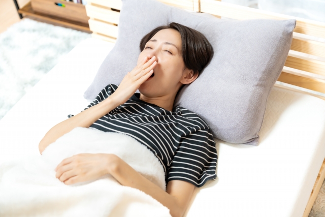 ベッドであくびする女性の画像